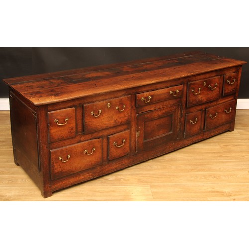 1614 - A George III vernacular oak low dresser, plank rectangular top above an arrangement of drawers and a... 