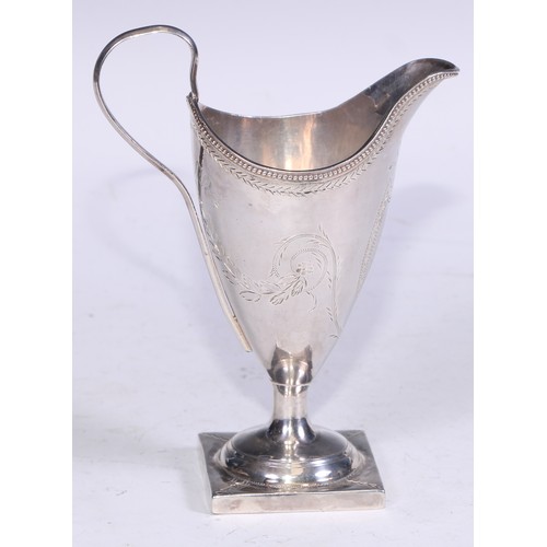 142 - A George III silver helmet shaped cream jug, bright-cut engraved with leafy swags and a ribbon-tied ... 