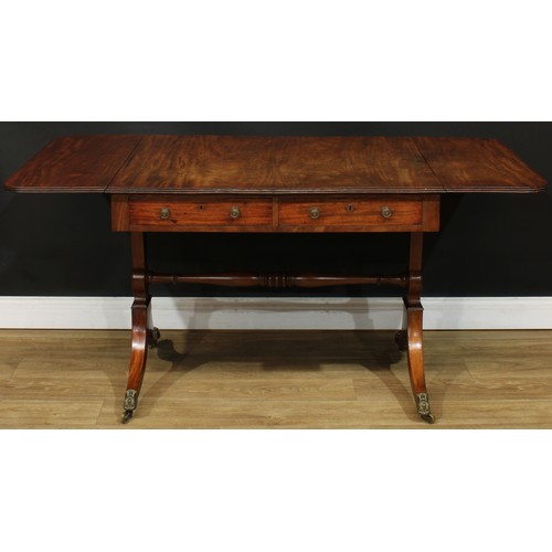 1767 - A Regency mahogany sofa table, rounded rectangular top with reeded edge and fall leaves above a pair... 