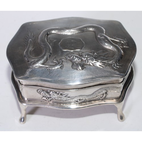 94 - A Chinese silver serpentine dressing table box, chased with ferocious dragons on a planished ground,... 