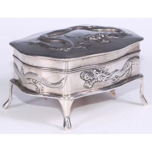 94 - A Chinese silver serpentine dressing table box, chased with ferocious dragons on a planished ground,... 