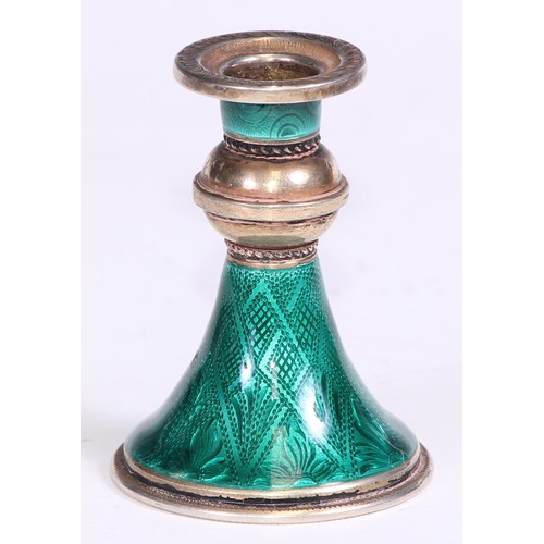 107 - A Continental silver-gilt and guilloche enamel taper stick, trumpet shaped base decorated in emerald... 
