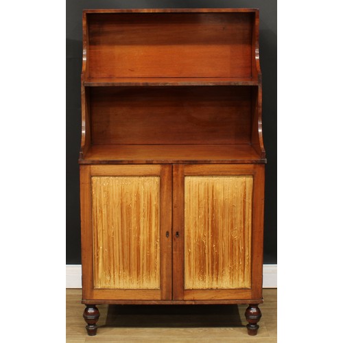 1770 - A Regency mahogany waterfall bookcase cabinet, shaped superstructure above a pair of doors enclosing... 