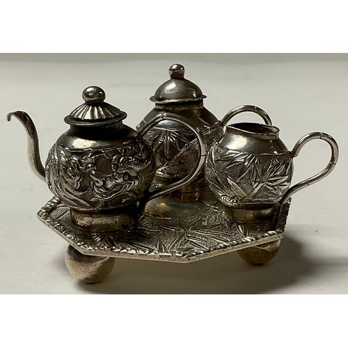 92 - A Chinese silver miniature three piece tea service on tray, chased with leafy bamboo,the octagonal t... 