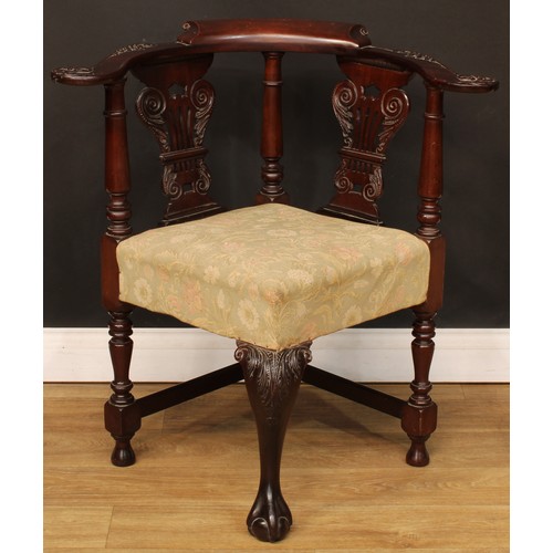 1658 - A George II Revival mahogany corner chair, curved cresting rail, the arms carved with scrolling acan... 