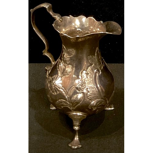 293 - A George III silver cream jug, embossed with floral sprays, vacant central cartouche, scroll handle,... 