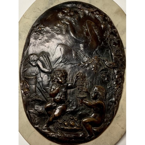 381 - An oval dark patinated bronze plaque, cast in low relief with putto harvesting and juicing grapes, 2... 