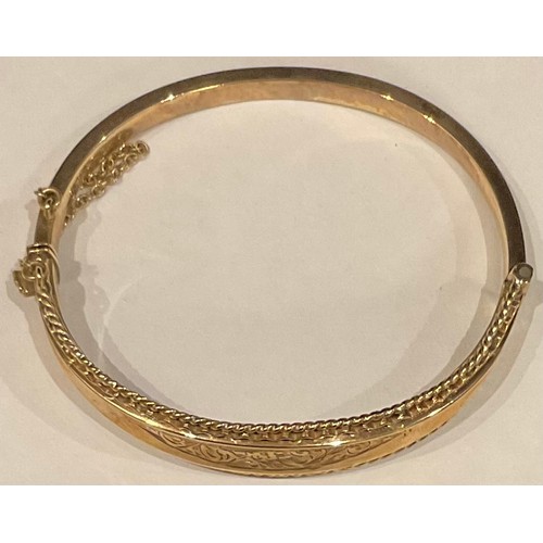 525 - A 9ct gold bangle, engraved and chased with foliate scrolls, Birmingham, 15.4g