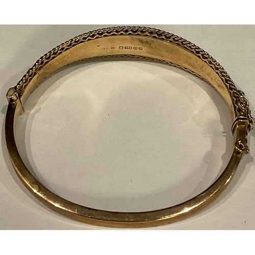 525 - A 9ct gold bangle, engraved and chased with foliate scrolls, Birmingham, 15.4g