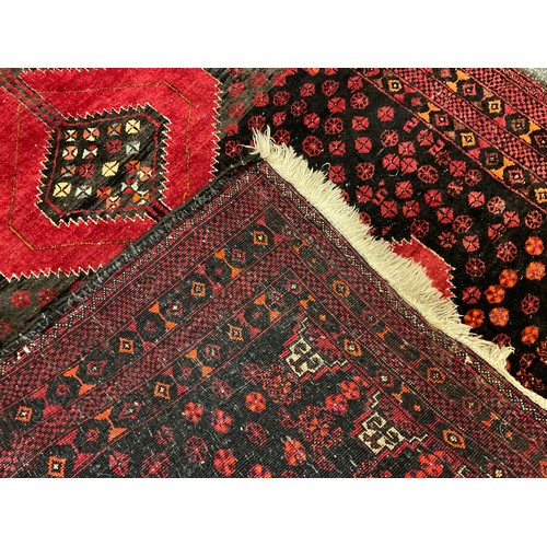 52 - An East Persian Balouch or Baluch rug / carpet, hand-knotted in deep red and black with a central ro... 