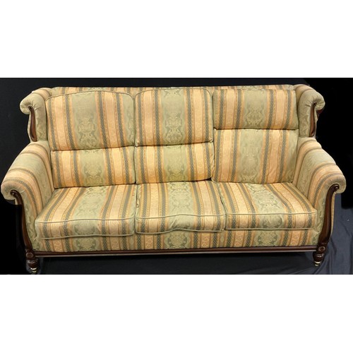 210 - A reproduction Victorian style three seater wing back sofa, floral stripped upholstery, shaped arms,... 