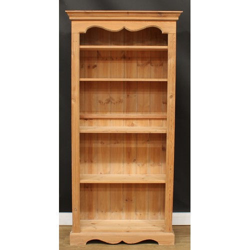 243 - A pine open bookcase, moulded cornice above four adjustable shelves, flanked by fluted stiles, plint... 