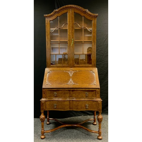 33 - A mid 20th century oak bureau bookcase, serpentine top with pair of glazed doors, three tiers of she... 