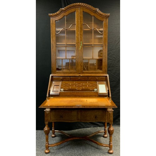 33 - A mid 20th century oak bureau bookcase, serpentine top with pair of glazed doors, three tiers of she... 