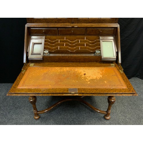 33 - A mid 20th century oak bureau bookcase, serpentine top with pair of glazed doors, three tiers of she... 