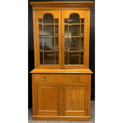 81 - An early 20th century light oak bookcase cabinet, moulded cornice, pair of astral glazed doors enclo... 