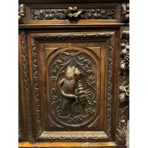 307 - An early 20th century French carved oak sideboard / Duodarn base, the over-sailing top above a pair ... 