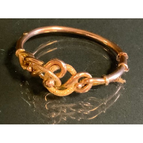 393 - A gold coloured metal scroll knot hinge bangle, stamped 9ct, 11.4g gross, cased