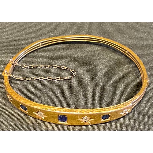 404 - A 15ct gold sapphire and diamond hinged bracelet, set with four diamonds and three  circular-cut sap... 