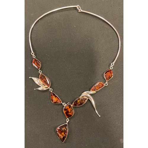 385 - An amber and silver pendant necklace, set with eight shaped amber lozenges within 925 silver leaf fr... 