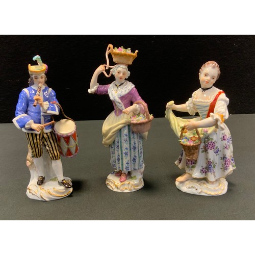 100 - A Meissen figure, of a musician, he stands wearing a feathered hat, playing a flute and holding a dr... 