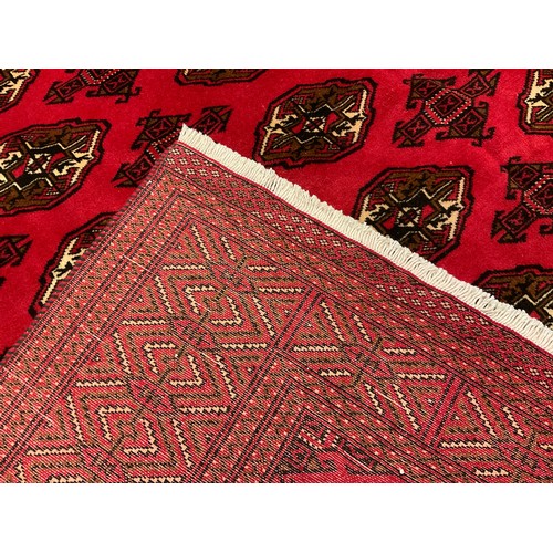 120 - A Turkoman rug / carpet, knotted in rich red, with a multi medallion field, wide stylised geometric ... 