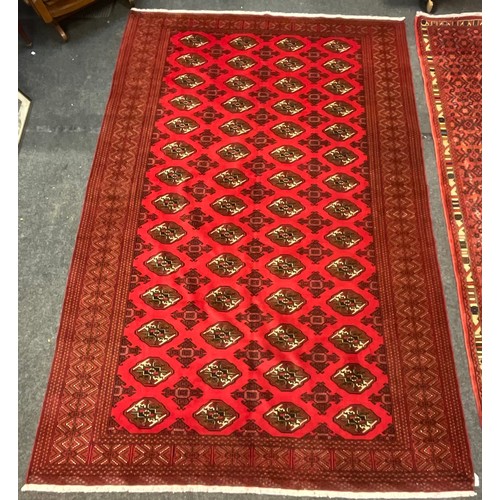 120 - A Turkoman rug / carpet, knotted in rich red, with a multi medallion field, wide stylised geometric ... 