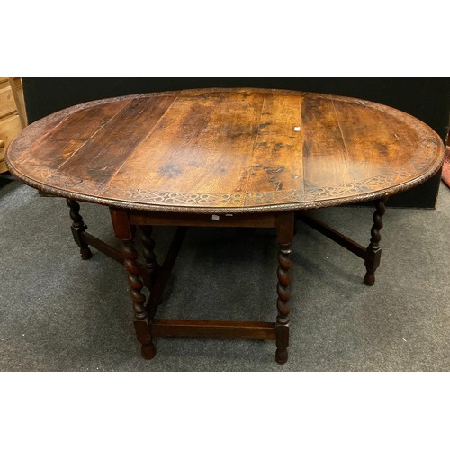 52 - A 19th century carved oak dropleaf dining table, the oval top carved with a love knot heart band, ba... 