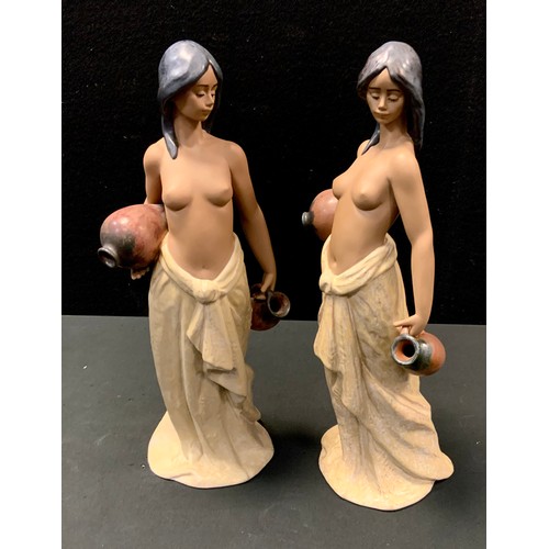 12 - A  pair of Lladro figures, Water Girl, no 2323, as a semi naked girl carrying a jug and vessel, scul... 