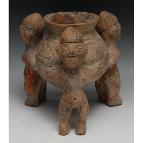 25 - A South American terracotta vessel, with three figures standing holding a vase, 23cm high