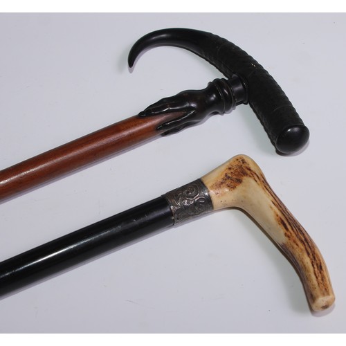 29 - An early 20th century walking stick, the horn handle carved with a hand gripping the hardwood cane, ... 