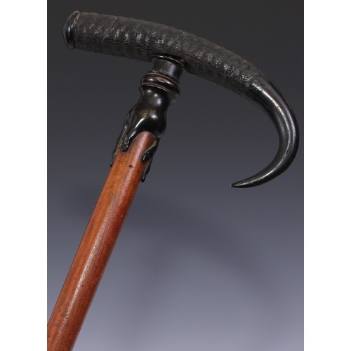 29 - An early 20th century walking stick, the horn handle carved with a hand gripping the hardwood cane, ... 