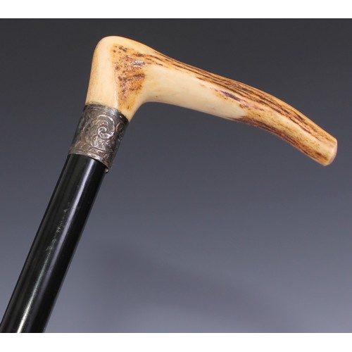 29 - An early 20th century walking stick, the horn handle carved with a hand gripping the hardwood cane, ... 