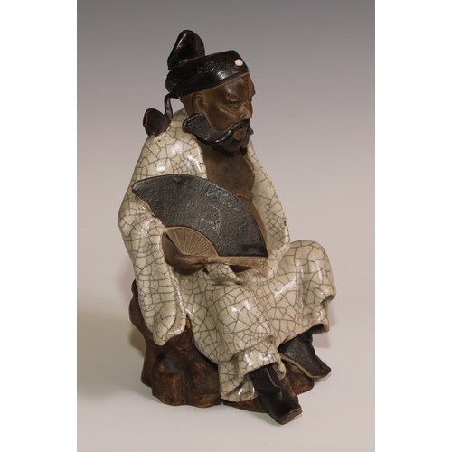 301 - A Chinese Shiwan stoneware figure, of an elder holding a fan, crackle glazed robe, 23.5cm high, earl... 