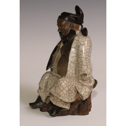 301 - A Chinese Shiwan stoneware figure, of an elder holding a fan, crackle glazed robe, 23.5cm high, earl... 