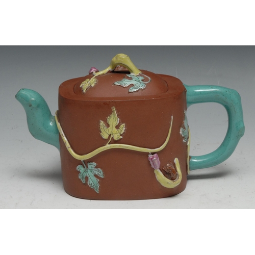 306 - A Chinese Yixing rounded rectangular wine pot moulded and picked out in coloured enamels with fruiti... 