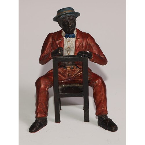 308 - A cold painted bronze, of a Mississippi dandy, finely dressed and seated backwards on a chair, 13cm ... 