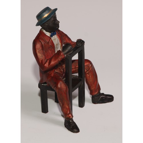 308 - A cold painted bronze, of a Mississippi dandy, finely dressed and seated backwards on a chair, 13cm ... 