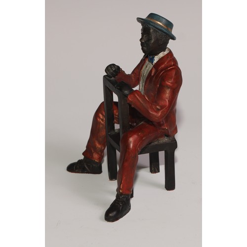 308 - A cold painted bronze, of a Mississippi dandy, finely dressed and seated backwards on a chair, 13cm ... 