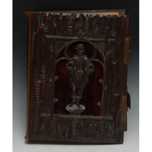 955 - A Black Forest musical photograph album, the cover pierced and carved as a farmer holding a pair of ... 