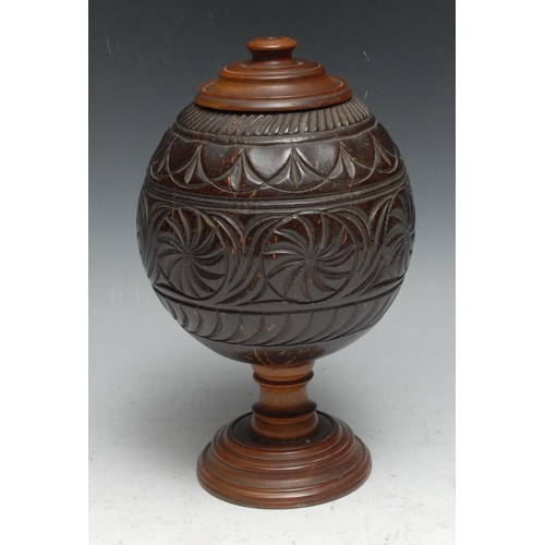 167 - A 19th century pedestal coconut cup, carved with roundels and lunettes, turned mahogany cover and ba... 