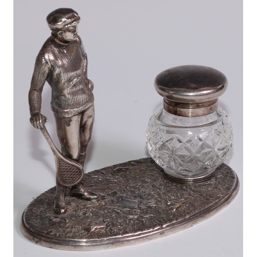 462 - A silver plated novelty inkstand, as a gentleman dressed for tennis, glass well, 12.5cm wide