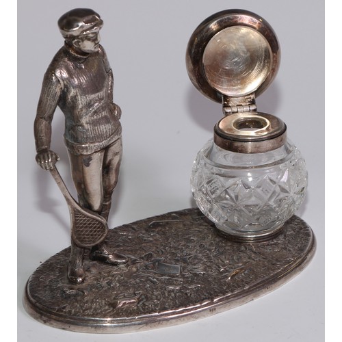 462 - A silver plated novelty inkstand, as a gentleman dressed for tennis, glass well, 12.5cm wide