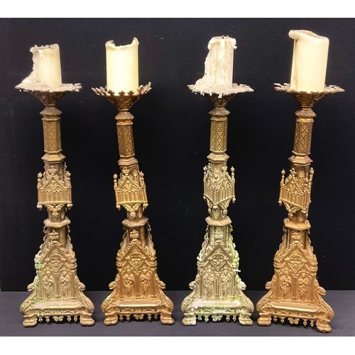 456 - A set of four Gothic Revival gilt metal altar pricket candlesticks, cast throughout with figures and... 