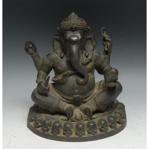 221 - Indian School, a verdigris patinated bronze, Ganesh on a Throne of Skulls, 24cm high, probably 19th ... 