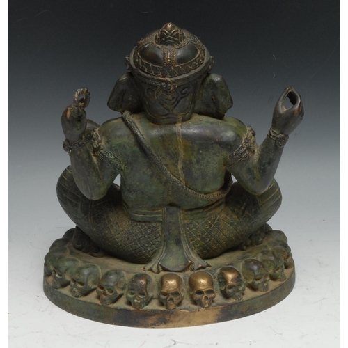 221 - Indian School, a verdigris patinated bronze, Ganesh on a Throne of Skulls, 24cm high, probably 19th ... 