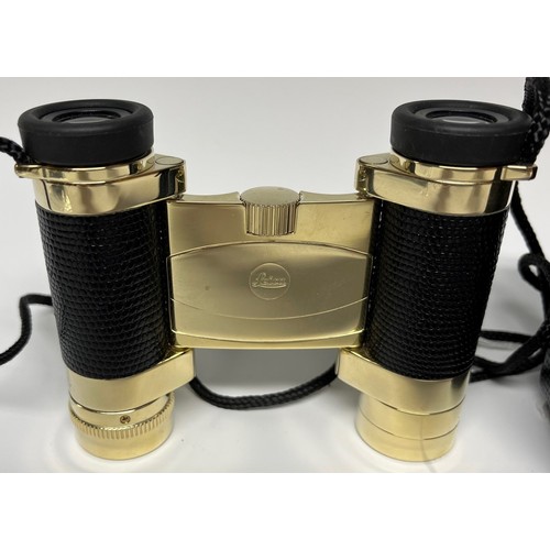 956 - A pair of Leica folding binoculars, faux black leather grips, gilt finish, 9cm long, cased