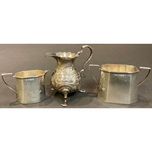 498 - A George II silver cream jug, embossed with landscapes, vacant central cartouche, scroll handle, sle... 