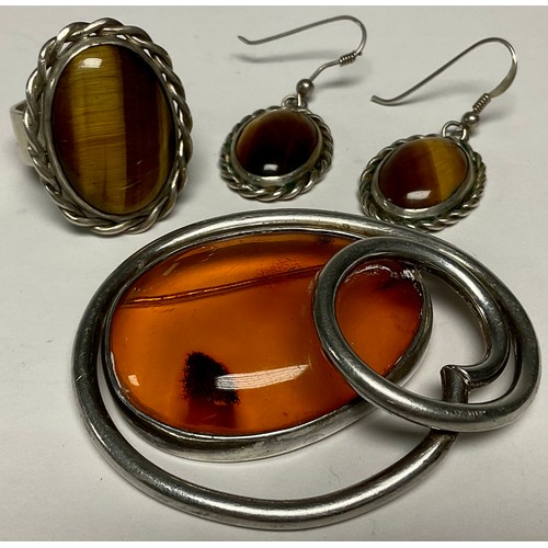 593 - A silver coloured metal and amber set brooch; a silver coloured metal tigers eye ring and earrings (... 