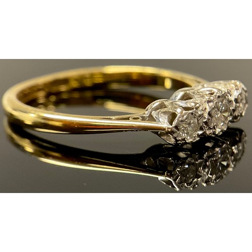 615 - An 18ct gold three stone diamond ring, the graduated brilliant cut stones illusion set in platinum, ... 